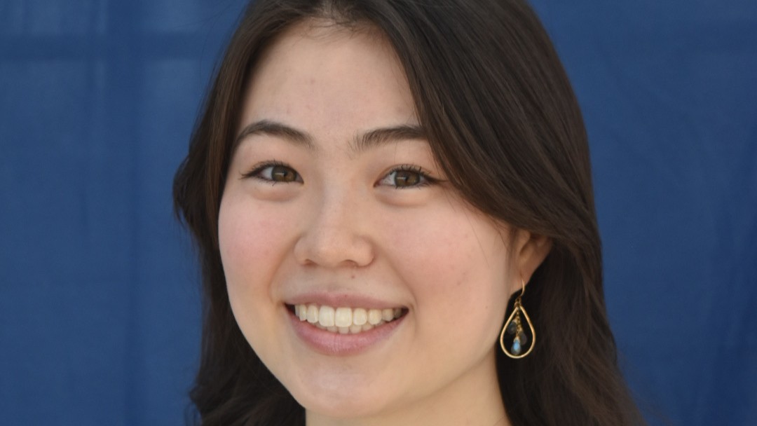 Kailey Lum smiles in front of a dark blue background.